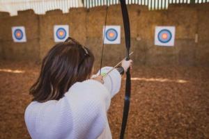 Una mujer sosteniendo un arco y una flecha frente a los objetivos. en 9 Eagles Eyrie, Camp Tapnell, en Yarmouth 26 fotos más