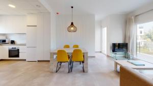 eine Küche und ein Esszimmer mit einem Tisch und gelben Stühlen in der Unterkunft Licuala by Oliva Nova in Oliva