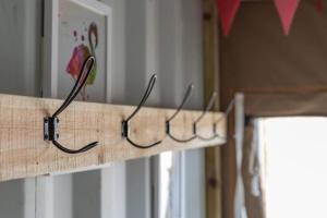 a wooden shelf with four hooks on it at Container 9, Camp Tapnell in Yarmouth +18 photos