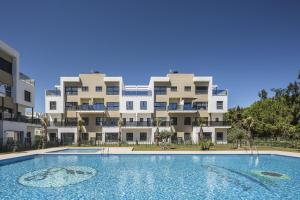 ein Apartmenthaus mit einem Pool davor in der Unterkunft Licuala by Oliva Nova in Oliva