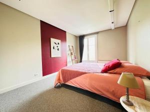 a bedroom with a bed and a red accent wall at Duplex Laon'Tre-Deux in Laon