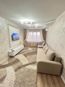 a living room with a couch and a tv at Двухкомнатные апартаменты на улице Естая, дом 83-1 напротив ТД Тулпар in Pavlodar