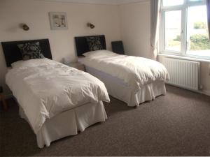a bedroom with two beds with white sheets and a window at Penarth Guest House in Par