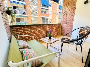 a balcony with a bench and a chair and a brick wall at Ecochic Apartment in Fuengirola Center in Fuengirola