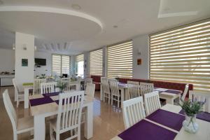 a restaurant with white tables and white chairs and windows at El Mare Hotel in Sarandë