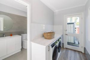 a white bathroom with a washing machine and a sink at KozyGuru Gold Coast Broadbeach Holiday Home in Gold Coast