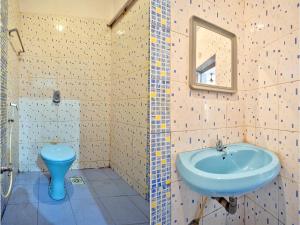 Om Sai Guest House في كالانغيُت: حمام مع حوض أزرق ومرحاض
