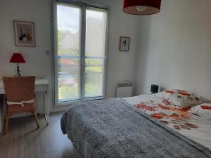1 dormitorio con cama, escritorio y ventana en Joli pavillon proximité ocean, en Saint-Nazaire