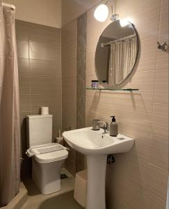 een badkamer met een wastafel, een toilet en een spiegel bij Galazia Nera Apartments in Áyios Andréas Messinias