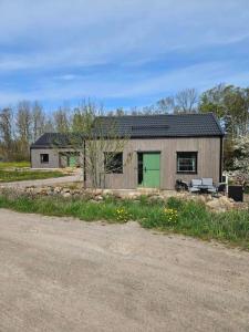 een klein gebouw met een groene deur op een weg bij Ebbas stuga in Färjestaden