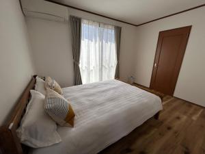 Un dormitorio con una gran cama blanca con ventana. en 近藤沢駅の新装リノベーション一軒家 3LDK、無料駐車場完備、最大7名様までご利用可能, en Fujisawa
