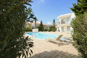a swimming pool with two lounge chairs and a house at Danaos complex in Paphos