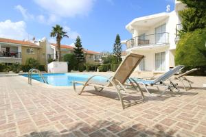 a pair of chairs sitting next to a swimming pool at Danaos complex in Paphos City