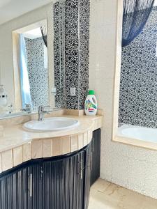 Fabulous Apartment in Marina Agadir في أغادير: حمام مع حوض ومرآة وحوض استحمام