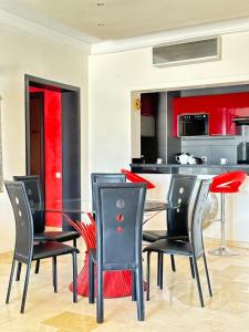Fabulous Apartment in Marina Agadir في أغادير: غرفة طعام مع طاولة زجاجية وكراسي سوداء