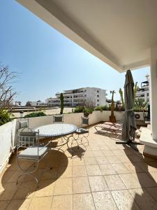 un patio con mesa, sillas y sombrilla en Fabulous Apartment in Marina Agadir en Agadir