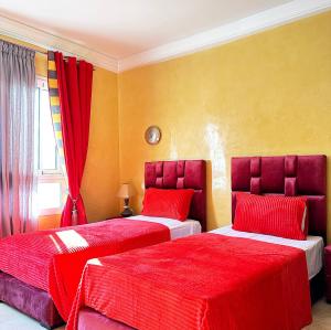 Fabulous Apartment in Marina Agadir في أغادير: غرفة نوم بسريرين ذات أغطية حمراء