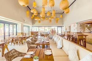 un restaurante con mesas y sillas de madera y ventanas en Mövenpick Resort Al Marjan Island, en Ras al Khaimah