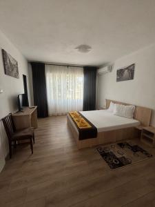 een slaapkamer met een bed, een stoel en een raam bij Casa RoxAmy in Orşova