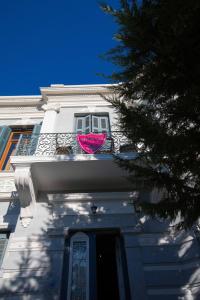 - un bâtiment blanc avec un parasol rose sur un balcon dans l'établissement Olympias Mansion Mitilini, à Mytilène