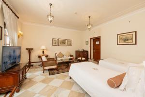 um quarto com uma cama, uma televisão e uma sala de estar em The Imperial, New Delhi em Nova Deli
