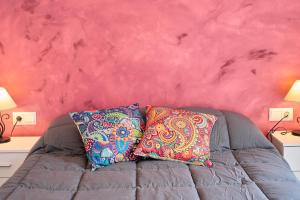 dos almohadas en un sofá contra una pared rosa en Apartamento La Molina, en Rute