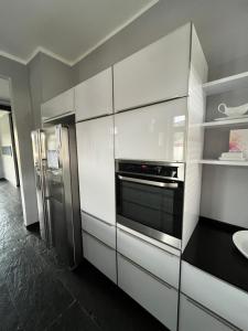 uma cozinha com armários brancos e um frigorífico de aço inoxidável em Traumhafte Wohnung mit Neckarblick und Balkon em Eberbach