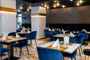 a dining room with tables and blue chairs at Hotel Szatmári & Étterem Jászberény in Jászberény