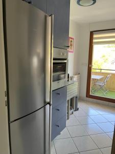 una nevera de acero inoxidable en una cocina con ventana en L’Aiglon, en Ribeauvillé