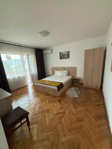een slaapkamer met een bed en een houten vloer bij Casa RoxAmy in Orşova