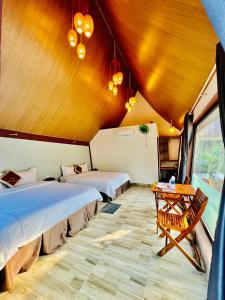 Habitación con 2 camas y mesa. en Tropical Valley Homestay en Phong Nha
