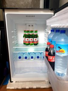 an open refrigerator with bottles of soda and water at BTN Mahkota Pemenang 13 Tamarin 3A in Pawenang