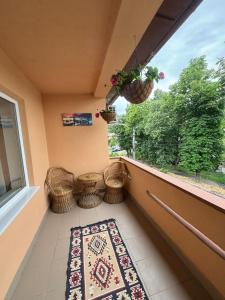 a balcony with a rug and wicker chairs and a window at Casa RoxAmy in Orşova