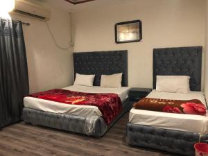 Defence-Mark-Hotel في لاهور: غرفة نوم بسريرين و اللوح الأمامي