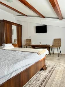 Schlafzimmer mit einem Bett, einem Schreibtisch und einem TV in der Unterkunft Parc Vatra Dornei 1 - Family, couples & groups in Vatra Dornei
