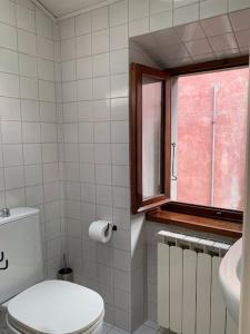 a bathroom with a toilet and a window at La Casa di Mezzo - The Middle House in Monte Marcello