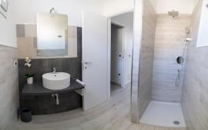 uma casa de banho com um lavatório, um espelho e um chuveiro em Appartamento Sorso em Sorso