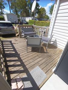 a wooden deck with two benches and a table at mobil home 3 chambres 152 in Pont-Aven