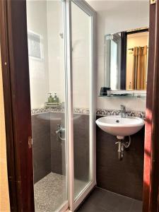 uma casa de banho com uma cabina de duche em vidro e um lavatório. em DINH DINH 2 AIRPORT HOTEL em Ho Chi Minh