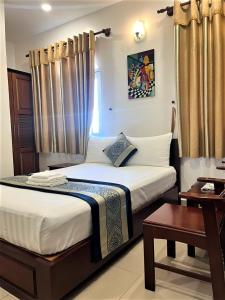 1 dormitorio con 1 cama grande con cortinas y mesa en DINH DINH 2 AIRPORT HOTEL en Ho Chi Minh