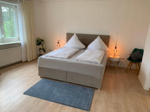 1 dormitorio con cama con almohadas blancas y alfombra azul en Landhaus Wiesemann Parkappartements & Dependance - Nähe Ettelsberg-Talstation, en Willingen