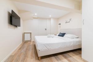 a white bedroom with a bed and a flat screen tv at Appartement Sous-Plex 4 Personnes Neuilly Maillot in Neuilly-sur-Seine