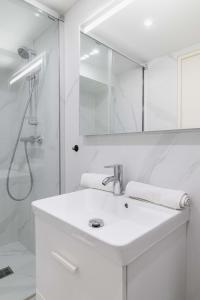 ein weißes Bad mit einem Waschbecken und einer Dusche in der Unterkunft Appartement Sous-Plex 4 Personnes Neuilly Maillot in Neuilly-sur-Seine