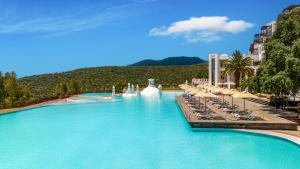 una piscina con sedie e ombrelloni in un resort di Kempinski Hotel Barbaros Bay Bodrum a Yaliciftlik