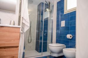 a bathroom with a toilet and a shower with blue tiles at Armarì Panoramic Flat in Vietri