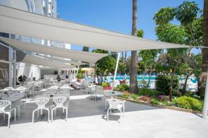 a patio with tables and chairs and a pool at Papouis Protaras Hotel in Protaras