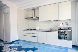 a kitchen with white cabinets and a blue tile floor at Armarì Panoramic Flat in Vietri