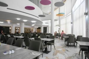 a dining room with tables and chairs and people at Papouis Protaras Hotel in Protaras