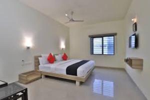 um quarto com uma cama com almofadas vermelhas e uma janela em ATITHI RESORT em Bharuch
