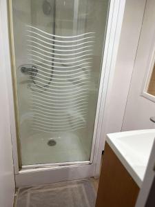 La salle de bains est pourvue d'une douche avec une porte en verre. dans l'établissement Mobil Home 4 / 6 personnes, à Nances